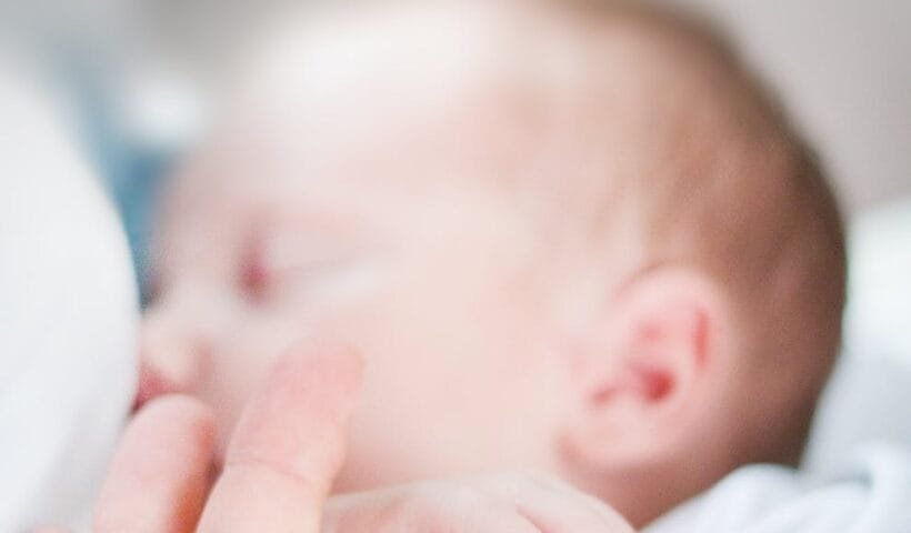 tilt shift lens photo of infant s hand holding index finger of adult