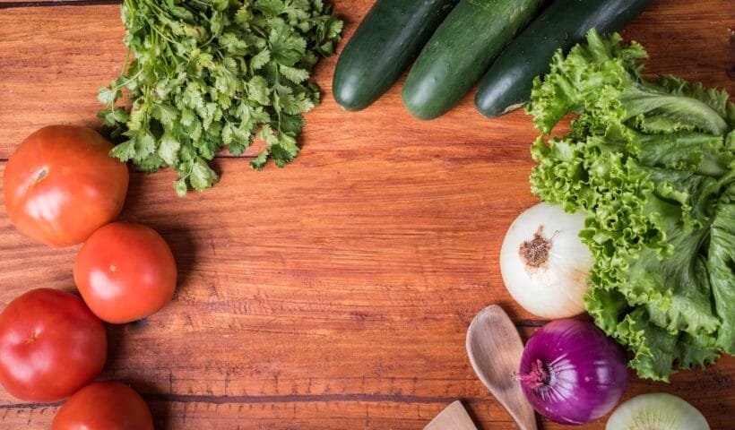 red tomato beside green vegetable on brown wooden table