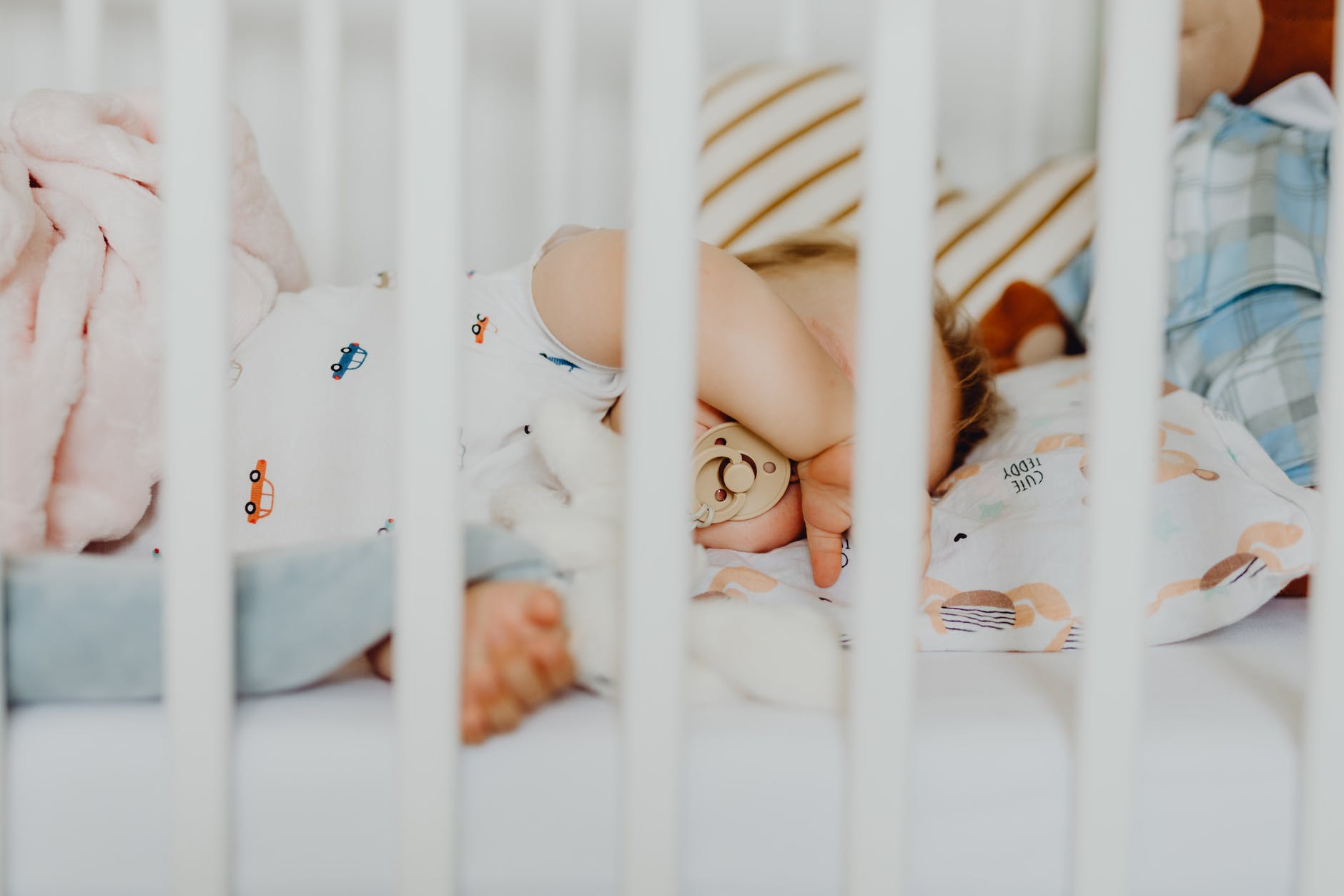 baby in white onesie lying on crib