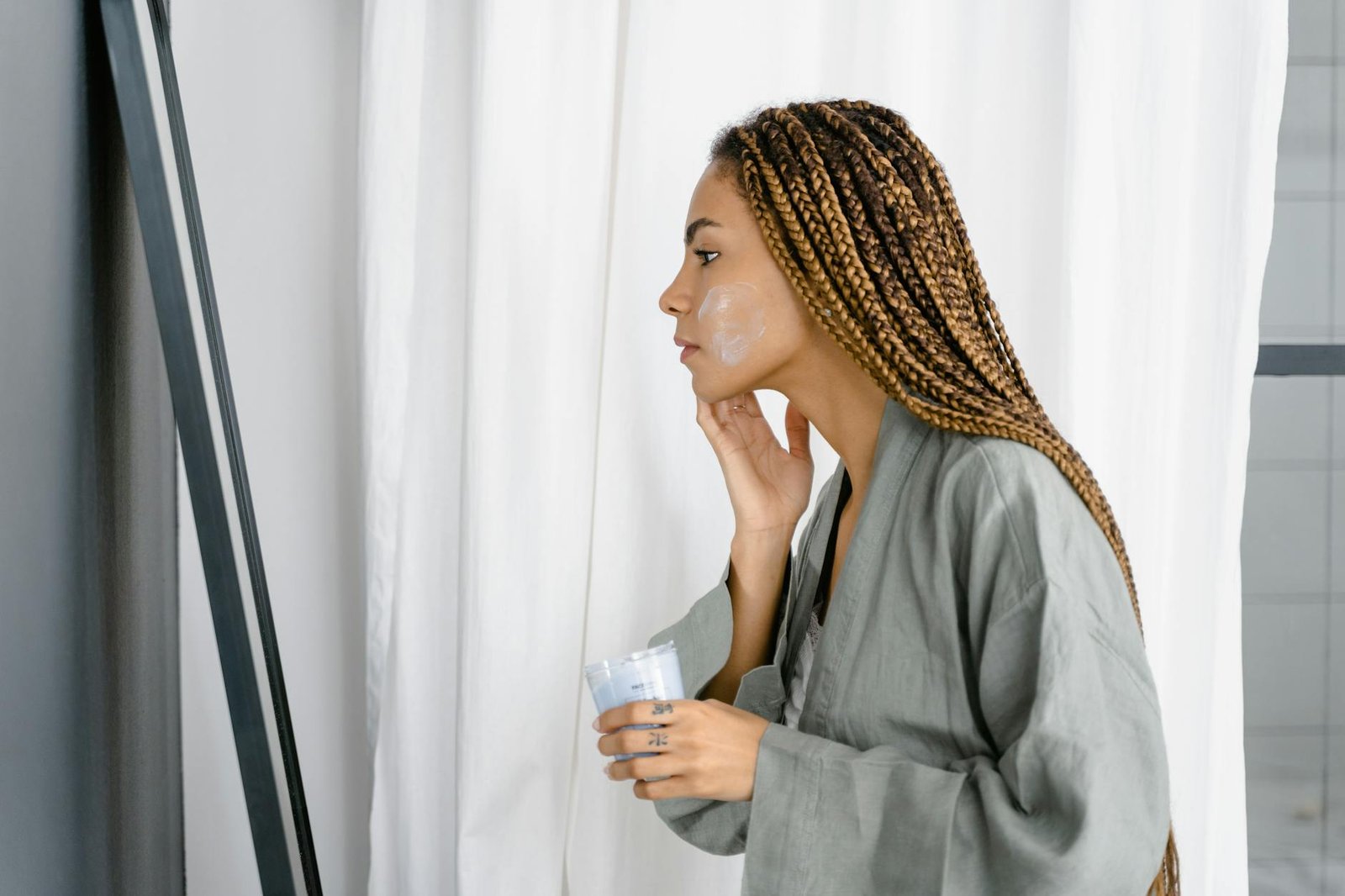 a braided hair woman applying a cream on her face