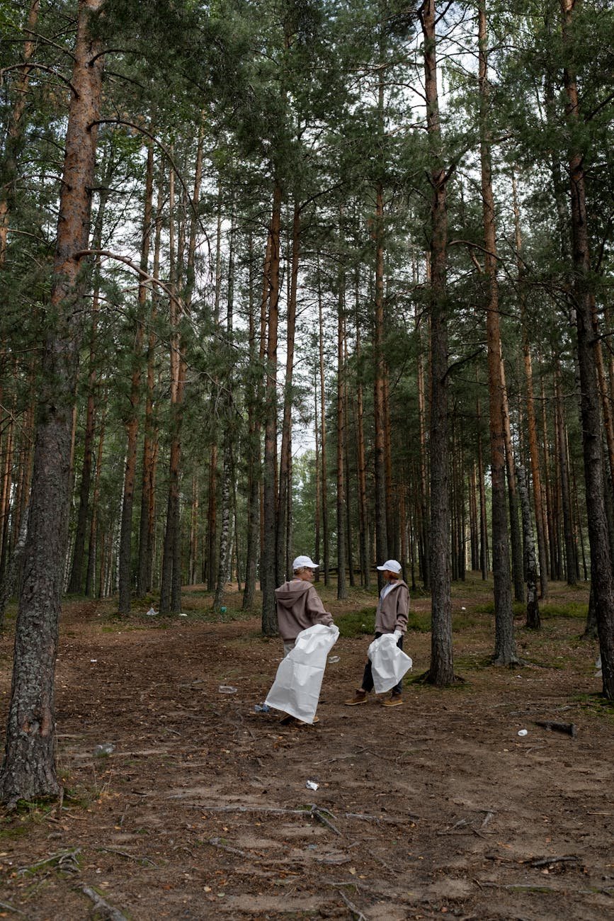 people holding white garbage bag in the forest