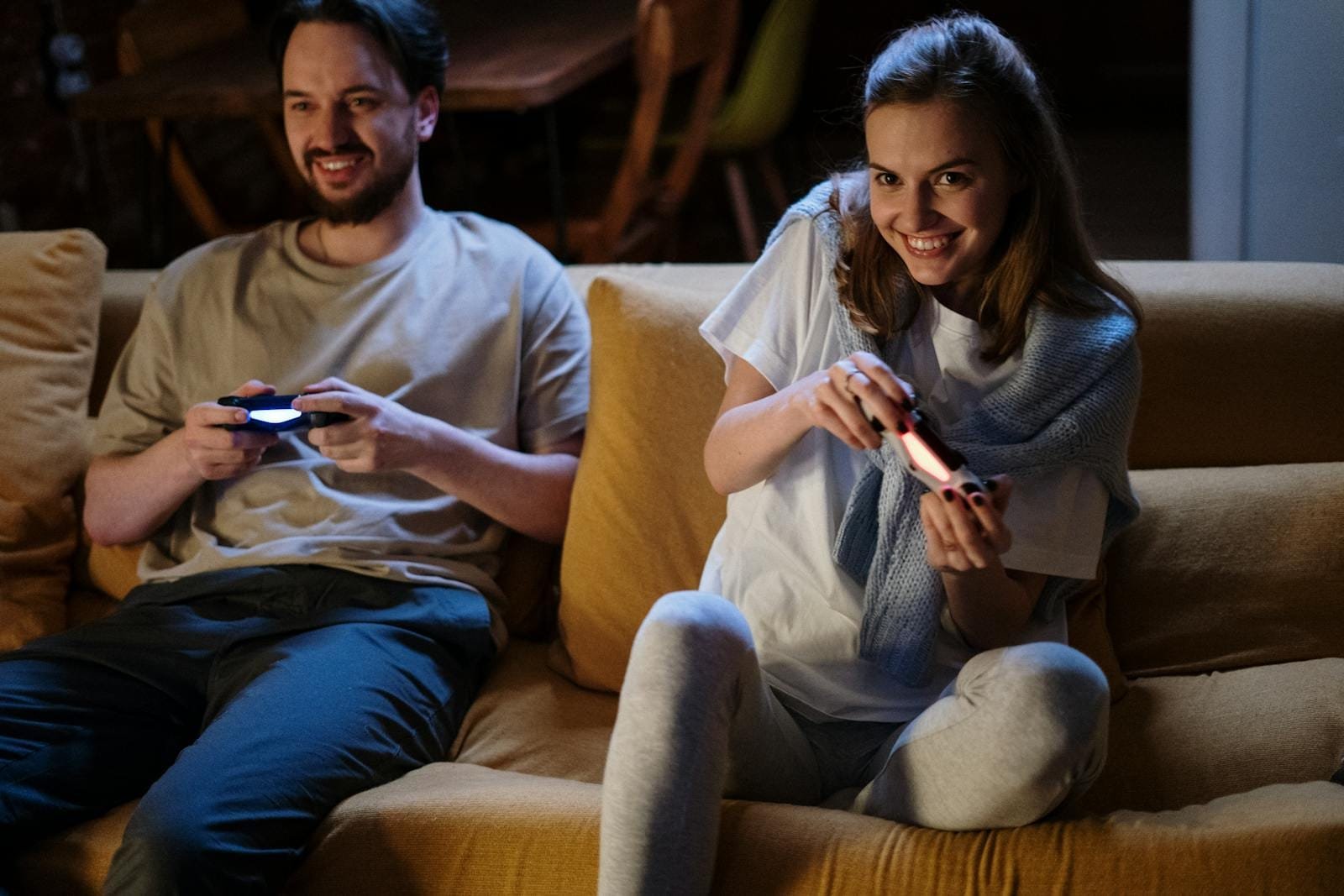 A happy couple plays video games on the sofa during a cozy evening at home.