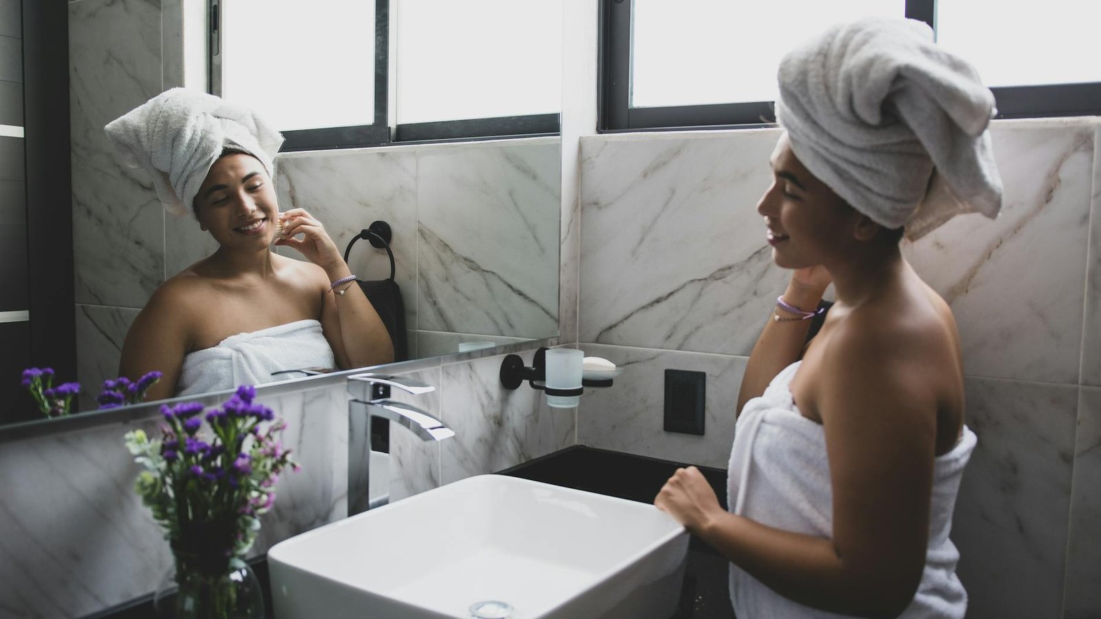 a woman in white bath towel looking at the mirror