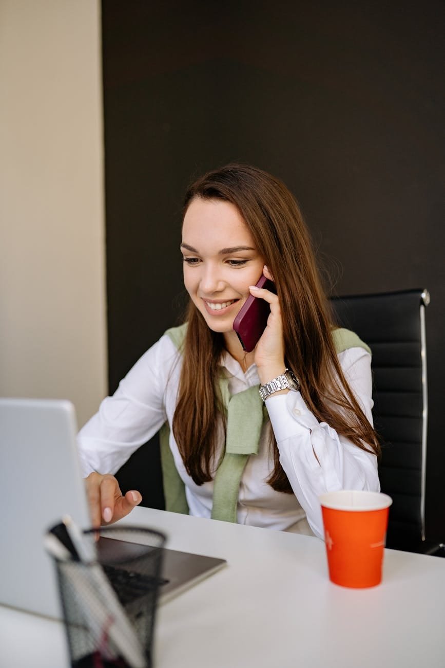 a woman on the phone while using a laptop
