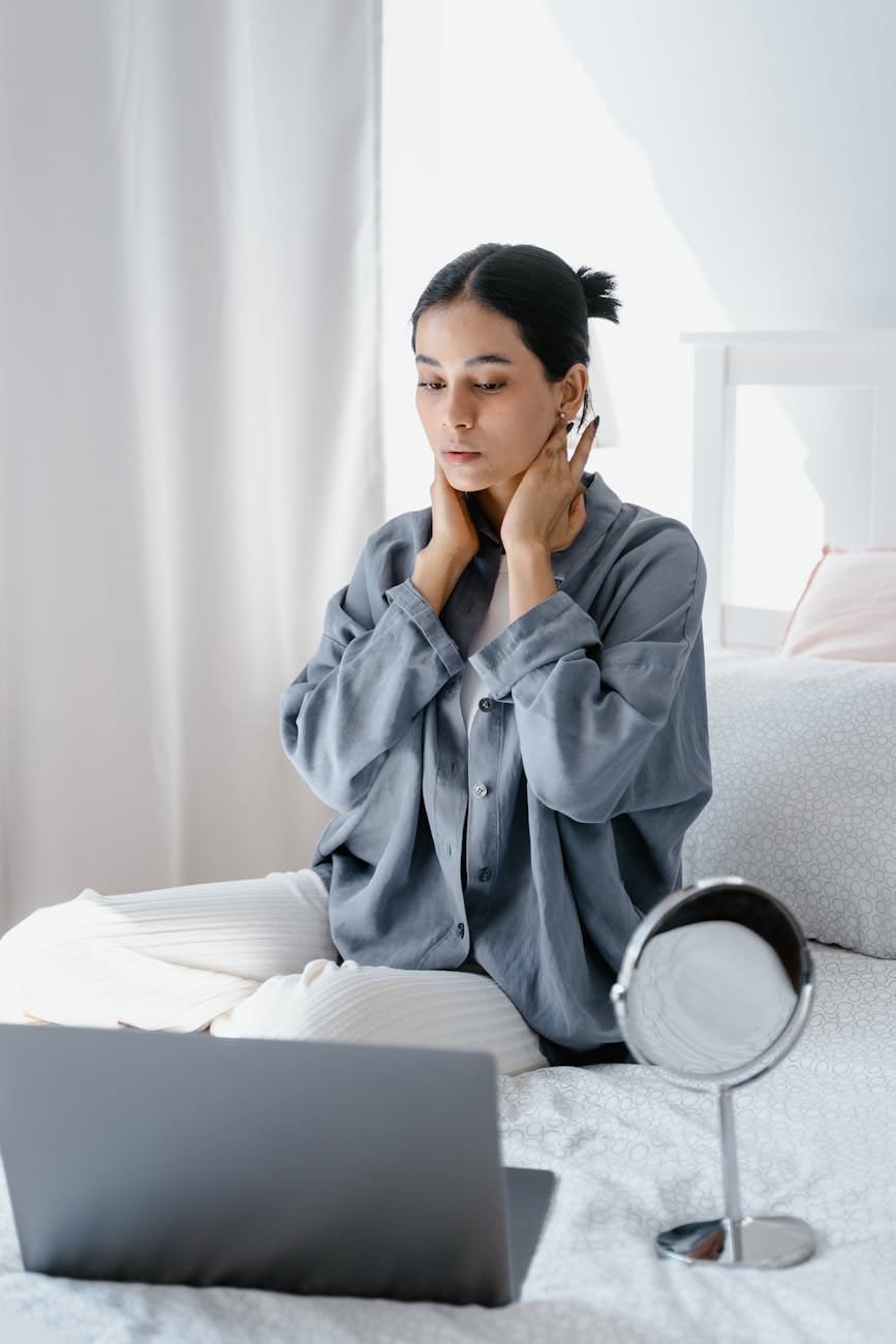a woman sitting on the bed while looking at laptop