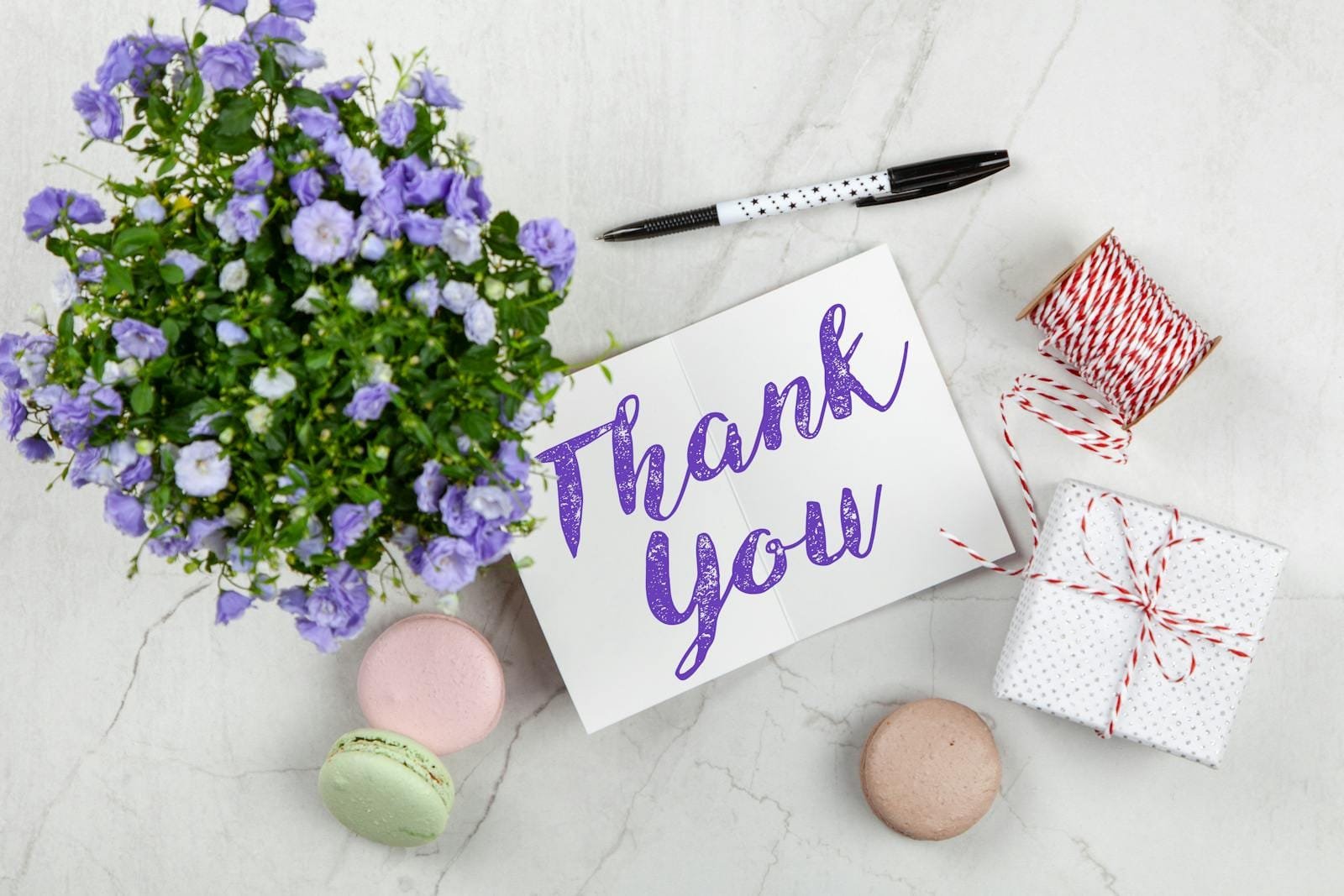 An elegant thank you card with flowers and a gift on a marble surface, perfect for expressing gratitude.