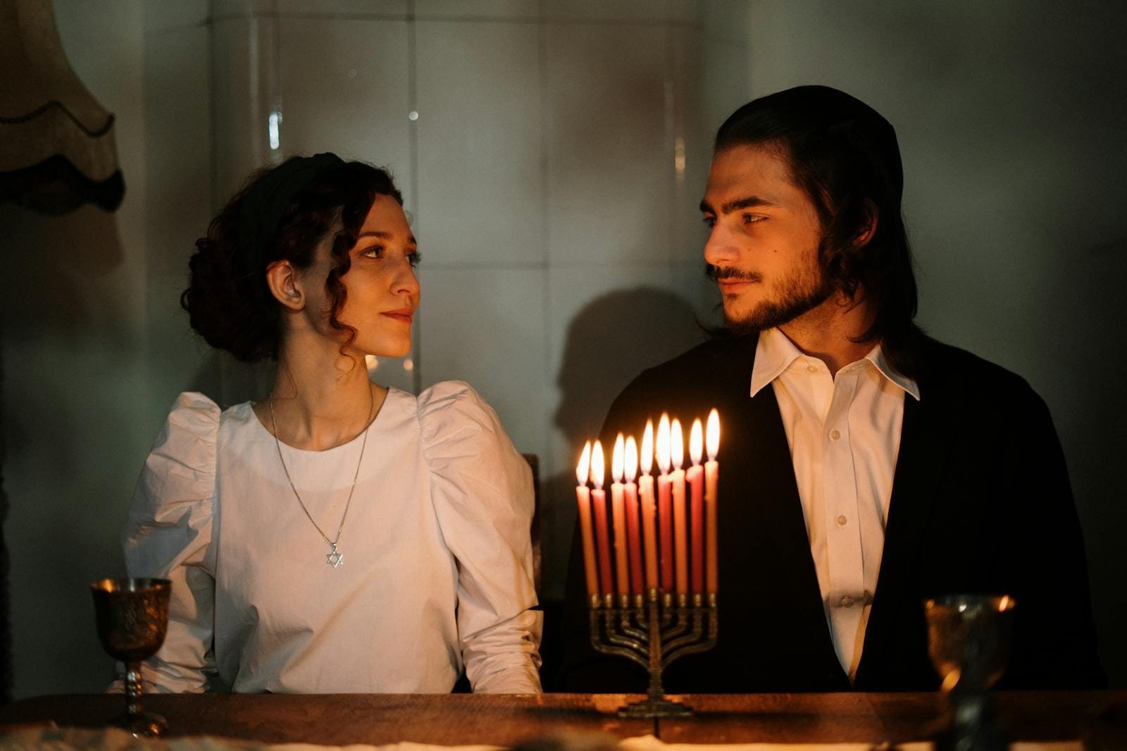 A couple enjoys a candlelit dinner celebrating Hanukkah with a menorah.