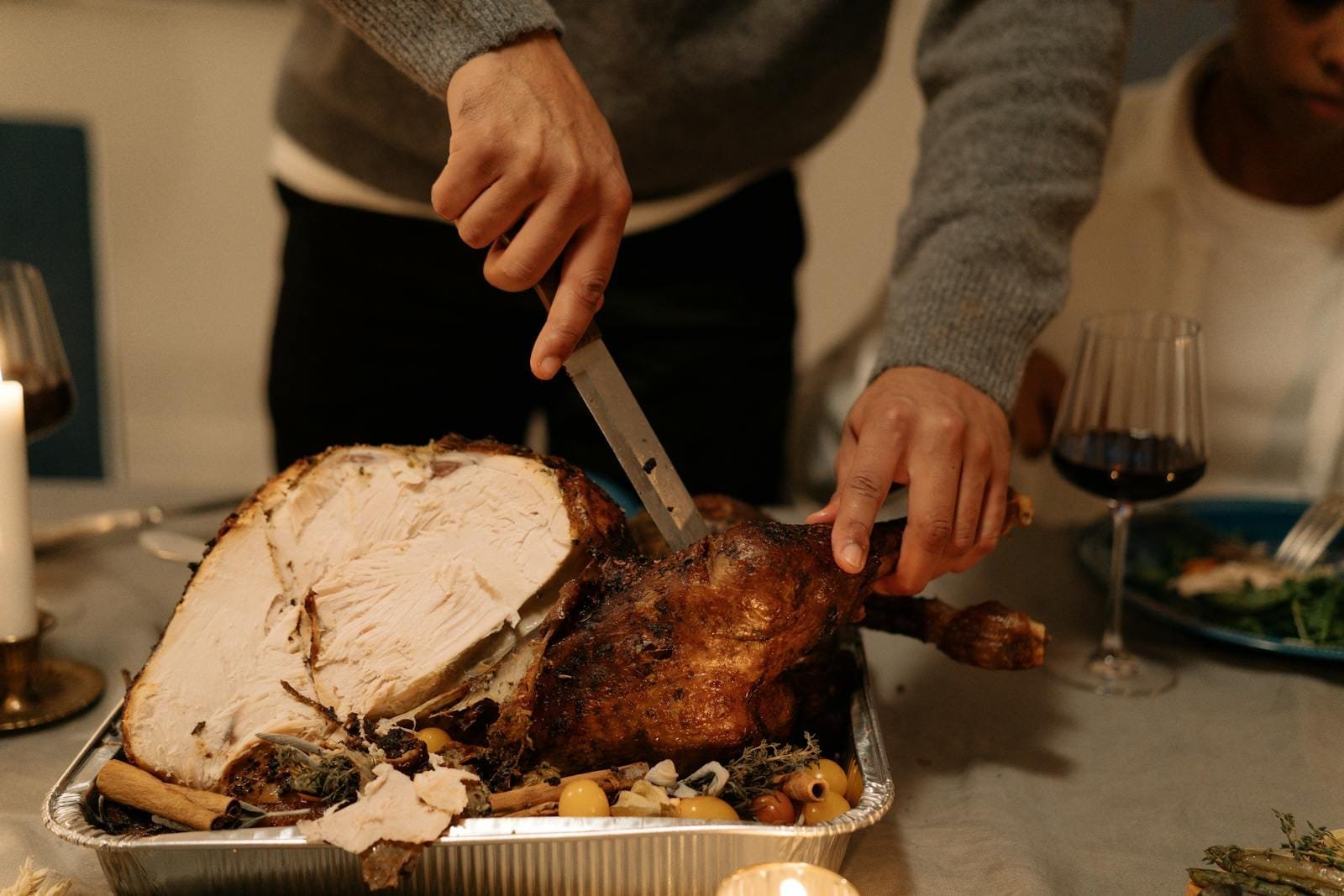 Person carving a delicious roasted turkey during a festive holiday dinner setting.